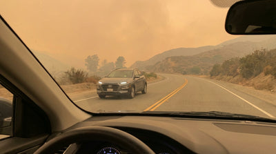 A car hire drives down a California highway with mountains obscured by a thick orange haze