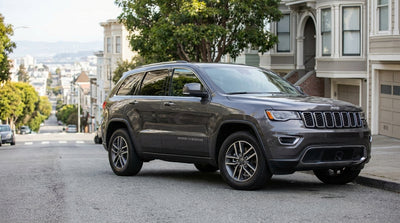 A silver car hire parked on a steep San Francisco hill with its wheels turned to the curb