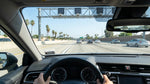 A modern car rental driving in the express lane on a busy Los Angeles freeway under a sunny sky