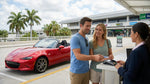 A traveler at a car hire counter inside Orlando Airport handing a payment card to an agent