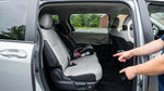 Parent installs a baby car seat in the backseat of a car rental on a leafy street in Pennsylvania