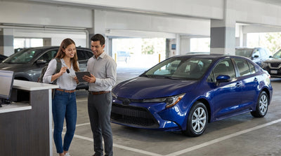 A young driver smiles from the front seat of a car rental on a busy street in New York City