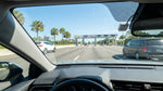 White car rental passing under an electronic toll gantry on a sunny Florida highway