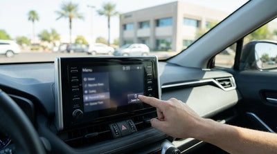 A driver's hand tapping the navigation screen of a United Estates car hire vehicle