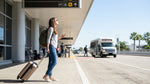 A car rental shuttle bus picking up passengers with luggage outside Terminal 2 in Los Angeles
