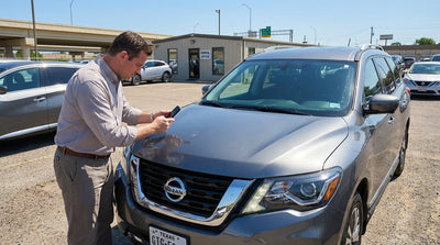 A modern car hire drives on a long, straight highway cutting through the wide-open landscape of West Texas
