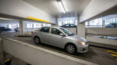 A compact car rental driving down a steep, sunny street in San Francisco with cable car tracks