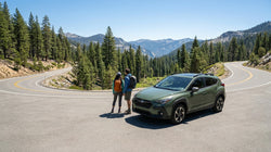 A white AWD SUV car rental driving on a snowy mountain pass in California