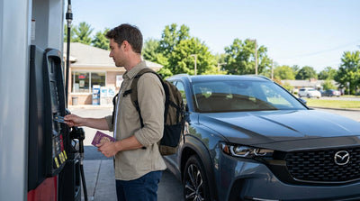 A person refueling their car rental at a gas station pump on a sunny day in Pennsylvania