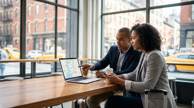 A silver car rental driving down a street in a bustling Pennsylvania city centre with skyscrapers in the background
