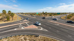 A car hire navigates the complex lanes and traffic signals of a continuous flow intersection in Texas
