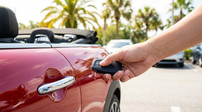A hand holding a key fob to unlock a car hire vehicle in a sunny Orlando lot with palm trees