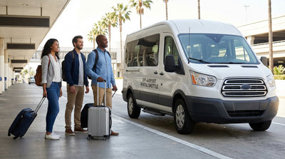 A car hire shuttle bus picks up travelers with luggage from a terminal curb at Los Angeles Airport