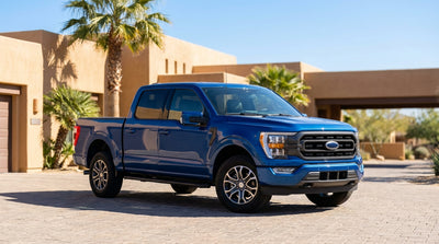 A silver car hire driving down a long, straight highway under the big blue sky of West Texas