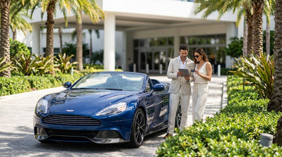 A luxury convertible car hire driving on a sunny, palm-lined road next to the ocean in Florida