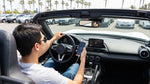 A person's hands connect a phone to the screen of a car rental dashboard to set up Android Auto in California