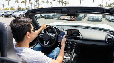 A person's hands connect a phone to the screen of a car rental dashboard to set up Android Auto in California