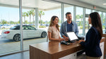 A smiling agent hands over keys for a car hire at a sunlit rental counter in Orlando