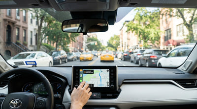 A car hire drives on a leafy New York parkway with a low arched stone bridge ahead
