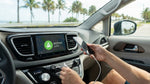 A person plugs a phone into the USB port of a car rental dashboard on a sunny day in Florida
