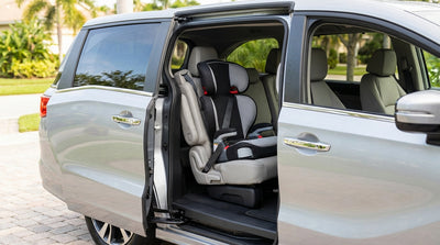 A parent secures their child in a booster seat in the back of their car rental for a safe family trip in Florida