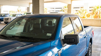 A modern car rental driving on a sunny Texas highway towards an overhead toll gantry
