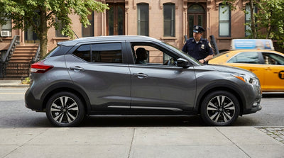 A modern car rental with tinted windows driving through traffic on a street in New York City