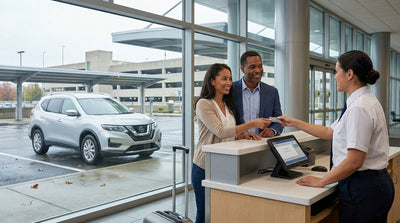 A person at a car rental counter in Pennsylvania hands their credit card to an agent to pick up their vehicle