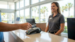 Close-up of a person handing a credit card to a clerk at a bright car rental desk in Florida