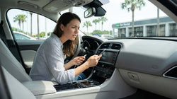 Driver holding a smartphone next to a blank dashboard screen inside an Orlando car rental vehicle