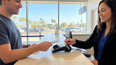 A red convertible car hire parked on a winding road overlooking the sunny California coast
