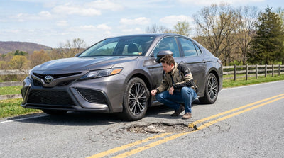 A driver inspects a damaged tire on their car rental on the side of a road in Pennsylvania