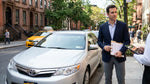 White car rental driving through busy New York City traffic with yellow cabs and tall skyscrapers