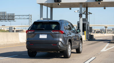 A car rental with a temporary paper plate driving under a toll gantry on a highway in Texas