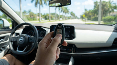 A driver holds a key fob with a low battery warning on the dashboard of their car rental in Florida