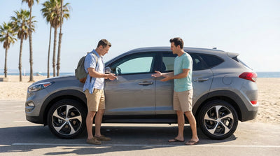 A driver holding a key fob stands beside their car hire in a sunny Los Angeles beach car park
