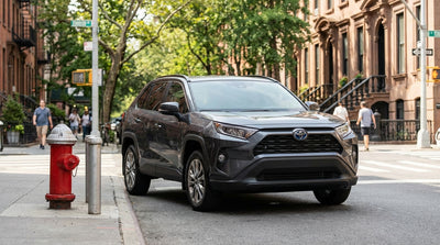 A blue car hire parked on a sunny New York street curbside, close to a red fire hydrant