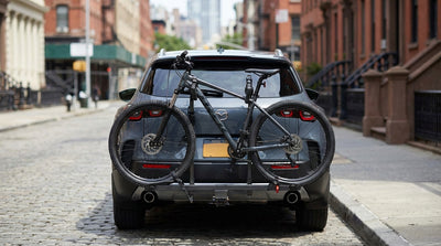 A car hire with a bike rack on the back is parked on a classic street in New York City