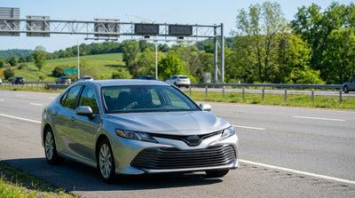 A car rental driving under a cashless toll gantry on the Pennsylvania Turnpike with green hills in the background