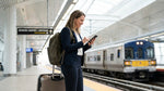 A person with luggage walks through a busy New York train station on their way to pick up a car hire