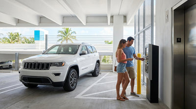 A white car hire parked in a multi-level garage with a sunny view of the Miami skyline