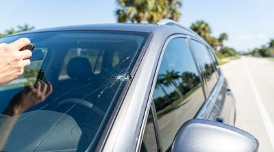 View from inside a car rental of a large crack spreading across the windscreen on a sunny Florida road