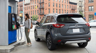 A modern white car rental parked on a street in New York with skyscrapers in the background