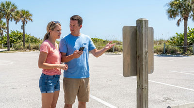 A tow truck lifting a car rental from a parking spot at a sunny Florida beach