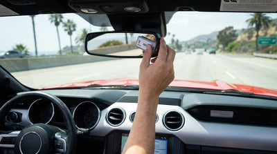 A person holds a FasTrak transponder inside their car rental, driving towards the Golden Gate Bridge in California