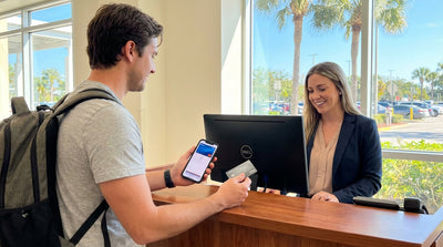 A red convertible car hire driving down a palm-tree-lined coastal road in sunny Florida