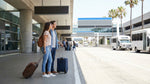Passengers with luggage waiting for a car hire shuttle outside Terminal 3 at LAX in Los Angeles