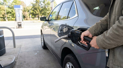 A hand holding a fuel pump nozzle to the capless filler of a car rental at a gas station in Pennsylvania