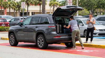 A sedan car hire stopped on a red curb marked 'Fire Lane' in front of a sunny Florida shopping plaza