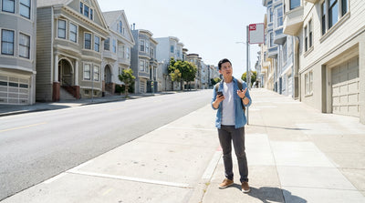 A red car hire parked on a steep San Francisco street with classic Victorian homes in the background